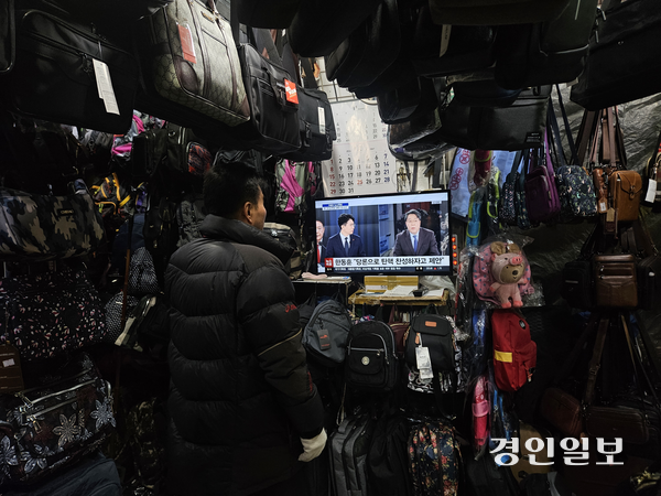 12일 수원 남문시장에서 가방가게를 운영하는 최모씨가 윤석열 대통령의 대국민 담화와 관련된 뉴스 프로그램을 시청하고 있다. 2024.12.12 /김지원기자 zone@kyeongin.com