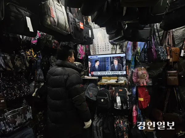 수원 남문시장에서 가방가게를 운영하는 최모씨가 윤석열 대통령의 대국민 담화와 관련된 뉴스 프로그램을 시청하고 있다. 2024.12.12 /김지원기자 zone@kyeongin.com