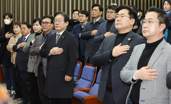 더불어민주당 이재명 대표(앞줄 왼쪽 여섯번째)와 박찬대 원내대표 등 참석한 의원들이 19일 국회에서 열린 비상의원총회에서 국기에 경례하고 있다. 2025.1.19 /연합뉴스