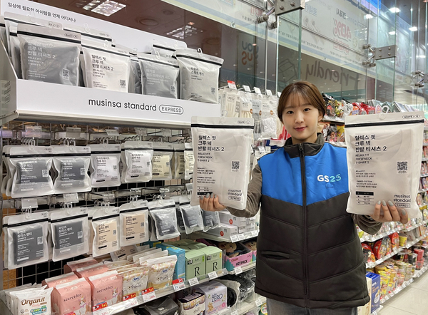 GS25 직원이 ‘무신사 스탠다드 익스프레스’ 제품을 들고 포즈를 취하고 있다. /GS리테일 제공