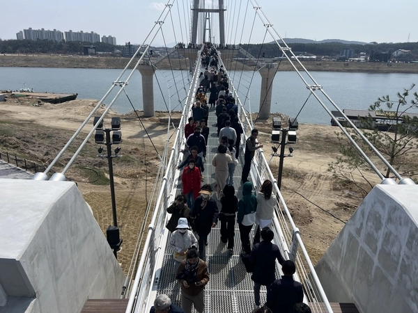 여주 남한강 출렁다리에 몰린 관광객들이 다리를 건너고 있다. 임시 운영 첫 주말에만 2만여 명이 방문한 이 다리는 국내 최장 보도 현수교로, 5월 1일 정식 개통을 앞두고 있다. 사진은 방문객들이 남한강을 가로지르는 출렁다리 위에서 봄 나들이를 즐기고 있다. 2025.4.6 / 여주세종문화관광재단 제공