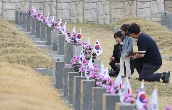 4·19혁명 기념일을 하루 앞둔 18일 서울 강북구 국립4.19 민주묘지 희생자 묘소 앞에서 한 부모가 자녀에게 당시 상황을 이야기해주고 있다. 2025.4.18 /연합뉴스