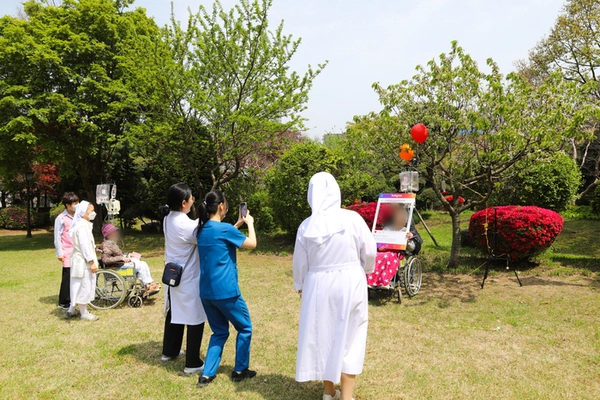 가톨릭대학교 성빈센트병원 호스피스완화의료센터가 최근 성빈센트 드 뽈 자비의 수녀회 정원에서 입원환자와 보호자를 위한 봄맞이 소풍 행사를 진행했다. 행사에 함께한 환자, 보호자, 의료진 등이 사진 촬영을 하는 모습. /가톨릭대학교 성빈센트병원 제공.