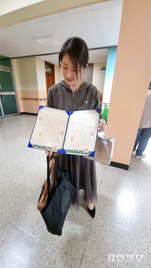 언남초 한 선생님이 15일 학부모가 전한 상장을 펴 보이며 아이들이 쓴 손편지를 보고 미소짓고 있다. 2025.5.15 /권순정기자 sj@kyeongin.com