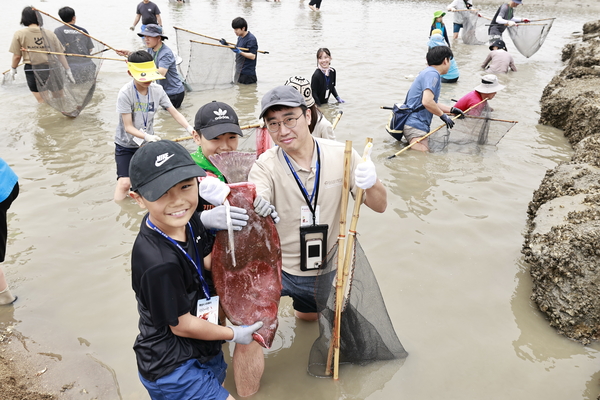 화성 뱃놀이 축제의 ‘독살 체험’ 프로그램에 참여한 가족이 직접 잡은 물고기를 들고 환하게 웃고 있다. 2025.5.30 /화성시 제공