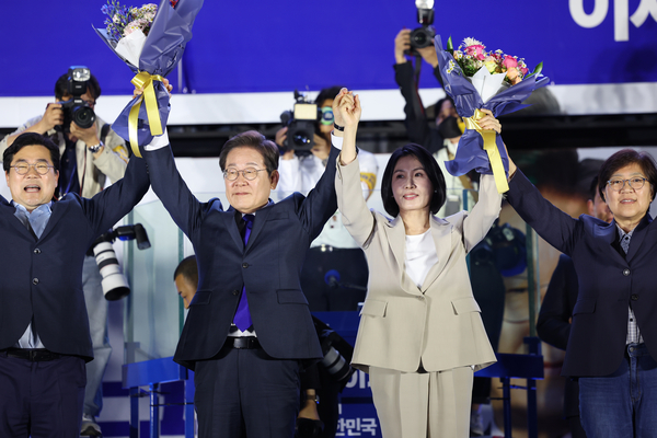 제21대 대통령 당선이 확실시되는 더불어민주당 이재명 대선 후보와 부인 김혜경 여사가 4일 서울 여의도 국회 인근에서 당 주최로 열린 국민개표방송 행사에 참석해 박찬대 상임총괄선대위원장과 정은경 총괄선대위원장단으로부터 꽃다발을 받고서 시민들을 향해 두 팔을 들어 인사하고 있다. 2025.6.4 /공동취재