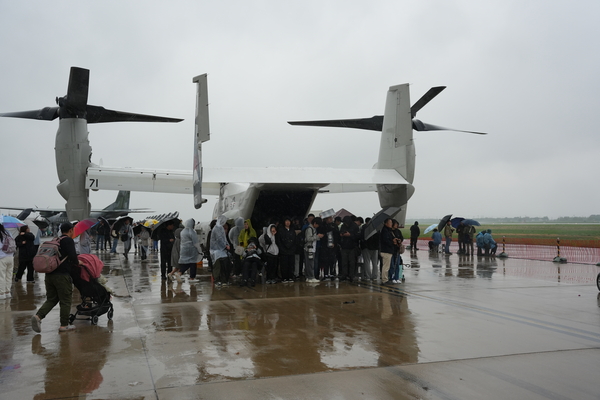지난 5월10일 열린 오산 에어쇼 현장에서 시민들이 비를 피하기 위해 전시 항공기 날개아래에 몸을 가린 채 추위에  떨고 있다. /독자 제공
