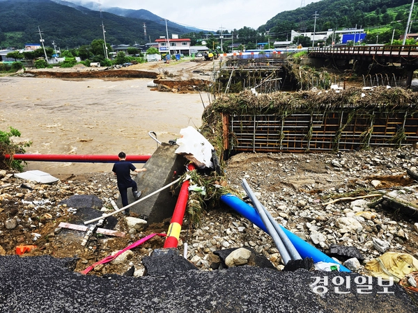 20일 밤 사이 내린 집중호우로 포천시 내촌면 내촌교 재가설공사 현장이 불어난 왕숙천 물에 공사자재들이 휩쓸려 어지럽혀져 있다. 인근 도로는 파손돼 형체를 알아볼 수 없다.  2025.7.20 포천/최재훈기자 cjh@kyeongin.com