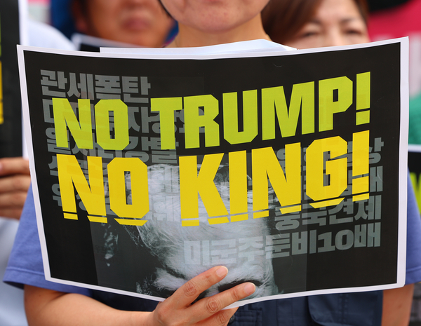 한미 관세협상이 타결된 31일 서울 광화문 미국대사관 인근에서 트럼프위협저지공동행동 및 농민의길 주최로 열린 입장발표 기자회견에서 한 참가자가 피켓을 들고 있다. 2025.7.31 /연합뉴스