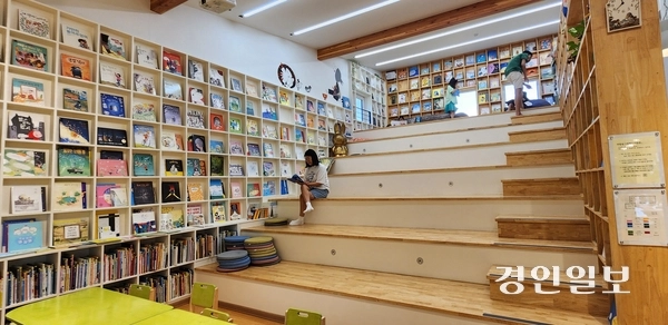 바람숲그림책도서관 내부. 계단식 열람 공간인 ‘들’과 계단 꼭대기 ‘산’에서 책을 보는 손님들. 2025.8.2 /김성호기자 ksh96@kyeongin.com