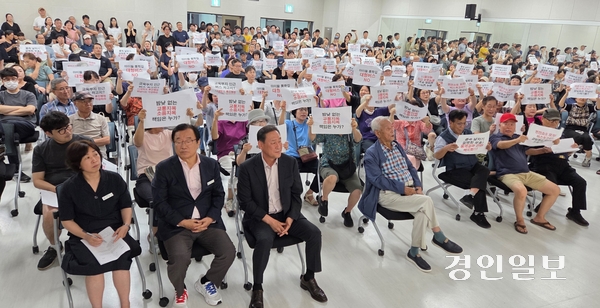 지난 14일 오후 7시 감일동 행정복지센터에서 열릴 예정이던 ‘하남시 서부권역 버스공영차고지 조성사업 타당성 검토 용역 결과’ 설명회가 1시간 만에 무산됐다. 이현재(맨 앞줄 왼쪽에서 두번째) 하남시장이 앉자 있는 가운데 감일지구 주민들이 반대 핏켓을 들고 있다. 2025.8.17 하남/문성호기자 moon23@kyeongin.com