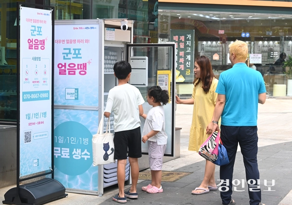 무더운 날씨가 이어진 18일 오후 군포시 산본로데오거리에 설치된 무인 냉장고 ‘군포 얼음땡’에서 시민들이 물을 가져가고 있다. 2025.8.18 /최은성기자 ces7198@kyeongin.com