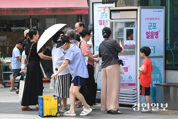 무더운 날씨가 이어진 18일 오후 군포시 산본로데오거리에 설치된 무인 냉장고 ‘군포 얼음땡’에서 시민들이 물을 가져가고 있다. 2025.8.18 /최은성기자 ces7198@kyeongin.com