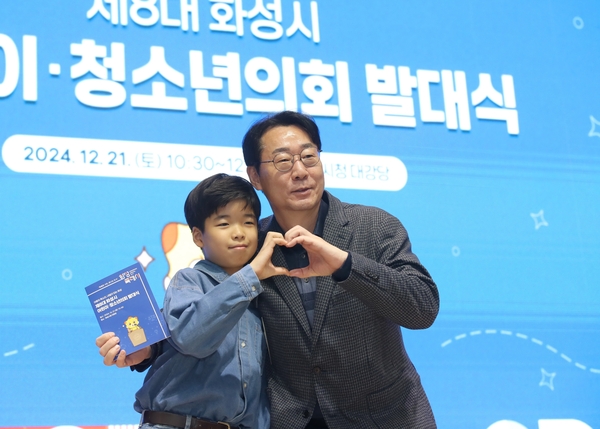 정명근 화성시장이 지난해 12월 열린 제8대 화성시 어린이·청소년의회 발대식에 참석, 한 어린이와 손하트를 만들며 기념촬영하고 있다. /화성시 제공