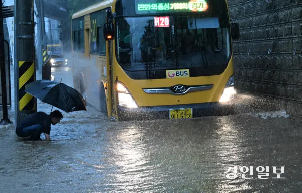 호우주의보가 발효 중인 16일 오후 화성시 병점동 송화초등학교 앞 버스정류장에서 한 시민이 폭우로 도로에 물이 차오르자 손으로 배수구를 뚫고 있다. 2025.9.16 /임열수기자 pplys@kyeongin.com