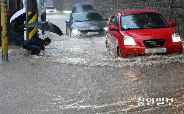 경기남부 지역에 호우주의보가 발령된 16일 오후 화성시 병점동 송화초등학교 앞 버스정류장에서 한 시민이 폭우로 도로에 물이 차오르자 맨손으로 막힌 배수구를 뚫고 있다. 2025.9.16 /임열수기자 pplys@kyeongin.com