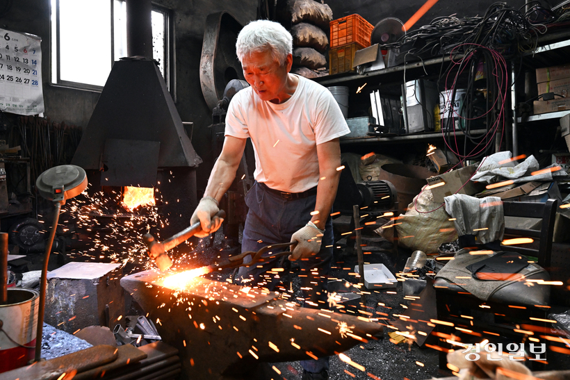 김영환 장인이 불에 달궈진 쇠를 망치로 내려치고 있다.