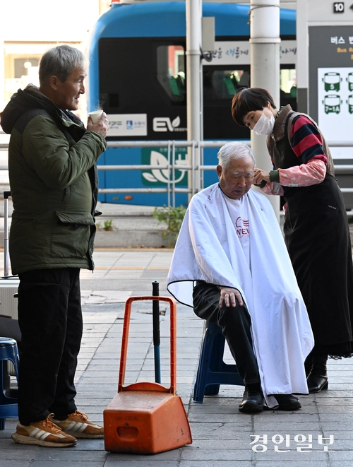 10일 오후 수원역 광장에서 한 봉사자가 노숙자에게 이발봉사를 해주고 있다. 2025.11.10 /임열수기자 pplys@kyeongin.com
