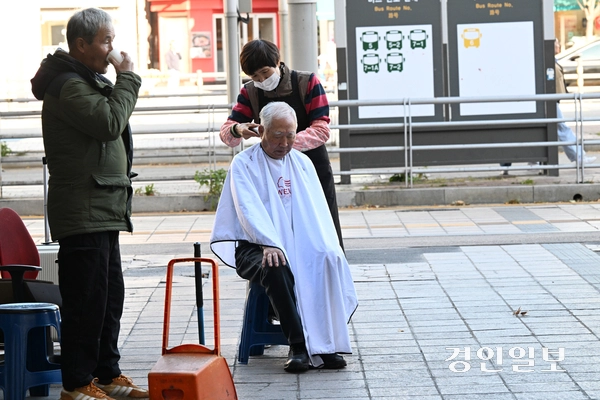 10일 오후 수원역 광장에서 한 봉사자가 노숙자에게 이발봉사를 해주고 있다. 2025.11.10 /임열수기자 pplys@kyeongin.com