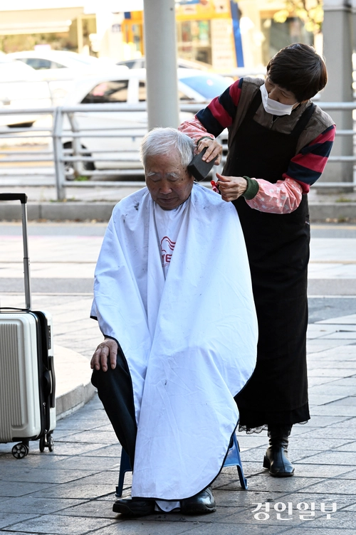 10일 오후 수원역 광장에서 한 봉사자가 노숙자에게 이발봉사를 해주고 있다. 2025.11.10 /임열수기자 pplys@kyeongin.com