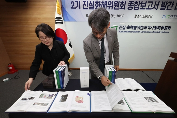 진실·화해를 위한 과거사 정리 위원회(진실화해위) 관계자들이 18일 서울 중구 진실화해위에서 열린 2기 진실화해위원회 종합보고서 발간 대국민 보고회에 앞서 책자를 펼쳐보이고 있다. 2025.11.18 /연합뉴스