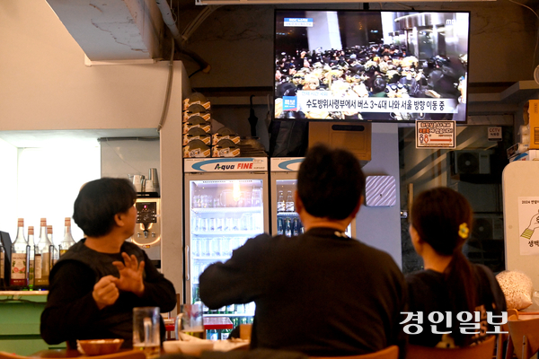 윤석열 전 대통령이 비상계엄령을 선포한 지난해 12월 3일 밤 수원시 권선구의 한 점포에서 시민들이 실시간 국회 상황 뉴스를 시청하고 있다. 2024.12.4 /최은성기자 ces7198@kyeongin.com