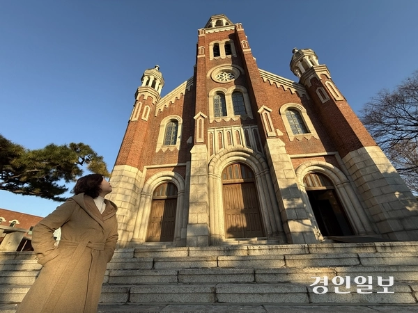 지난 5일 오후 인천 답동성당 앞에서 종탑 쪽을 바라보고 있는 양진채 작가. 신작 ‘언제라도 안아줄게’의 주요 배경이기도 하다. 2025.12.5 /박경호기자 pkhh@kyeongin.com