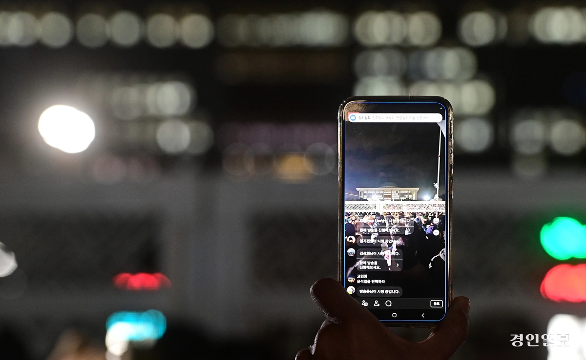 윤석열 전 대통령이 비상계엄을 선포한 2024년 12월 3일 서울 여의도 국회의사당 인근 도로에서 한 시민이 라이브 방송으로 국회상황을 알리고 있다. 2024.12.4 /조재현기자 jhc@kyeongin.com