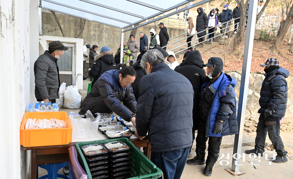 경기불황 속에 물가 상승 등으로 경기도 내 무료급식소들이 운영난을 겪고 있다. 12일 오전 수원시 팔달산 무료급식소 ‘사랑의 집’에서 노숙인 등 취약계층들이 도시락을 받고 있다. 2026.1.12 /임열수기자 pplys@kyeongin.com