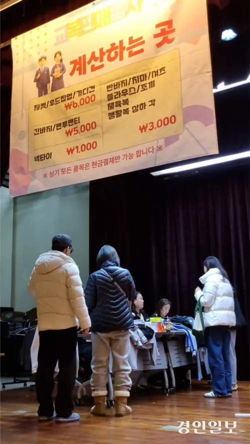 ‘줍줍’한 장자중 교복 10여벌을 들고 계산대 앞에선 A씨(흰색점퍼). 가격표를 보면 10만원~20만원에 이르는 교복 자켓도 6천원에 장만할 수 있다. 2026.2.6 구리/권순정기자 sj@kyeongin.com