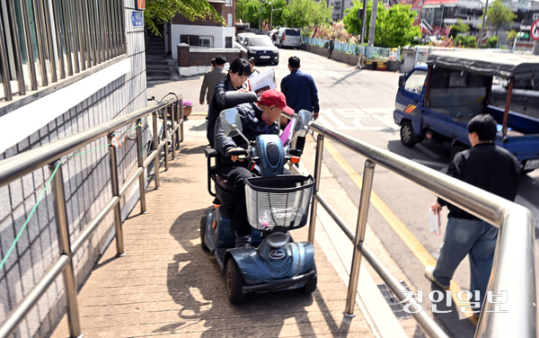 전동휠체어를 타고 제9회 지방선거 투표소를 점검하기 위해 수원시 권선구 버드내경로당을 찾은 전화진(74)씨가 가파른 경사로를 힘겹게 오르고 있다. 2026.4.23 /임열수기자 pplys@kyeongin.com