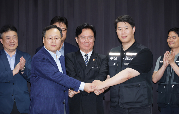 20일 경기도 수원시 장안구 경기고용노동청에서 열린 삼성전자 임금협상을 마친 후 여명구 삼성전자 DS(디바이스솔루션·반도체 사업 담당) 피플팀장과 최승호 삼성그룹 초기업노동조합 삼성전자지부 위원장이 잠정 합의안에 서명한 후 김영환 고용노동부 장관과 손을 맞잡고 있다. 2026.5.20 /공동취재
