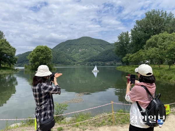 지난 23일 개막한 가평군 자라섬 꽃 페스타를 찾은 시민들이 북한강에 띄어진 돛단배를  촬영하고 있다. 축제가 열리는 남도 약 11만㎡ 규모 정원에는 양귀비, 아이슬란드 포피, 델피니움, 로벨리아, 콜레우스, 맨드라미 등 다양한 봄꽃과 초화류 등이 조성됐다. 2026.05.25 가평/김민수기자 kms@kyeongin.com