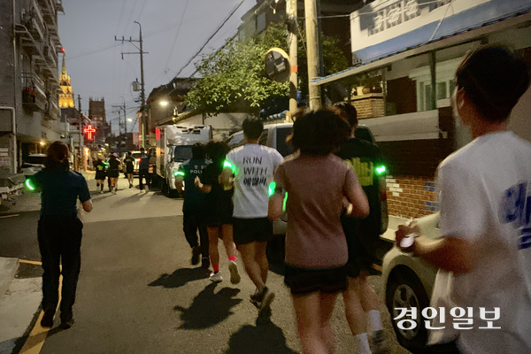 지난 25일 저녁 수원시 팔달구 골목 일대를 달리는 ‘팔달 나이트런’ 참가자들. 팔에 야광 표식을 달고 경찰관과 나란히 뛰었다. 주민 불편을 최소화하기 위해 조용히 달리다 위험 지점이 나오면 멈춰 서서 살폈다. 2026.6.25 /유혜연기자 pi@kyeongin.com