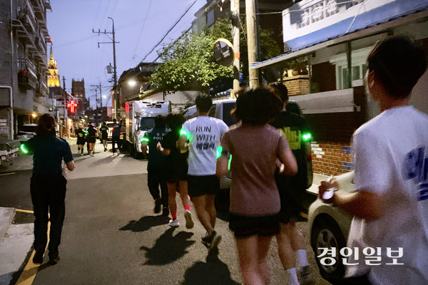 지난 25일 저녁 수원시 팔달구 골목 일대에서 ‘팔달 나이트런’ 참가자들이 팔에 야광 표식을 달고 경찰관과 나란히 달리고 있다. 주민 불편을 최소화하기 위해 조용히 달리다 위험 지점이 나오면 멈춰 서서 살폈다. 2026.6.25 /유혜연기자 pi@kyeongin.com