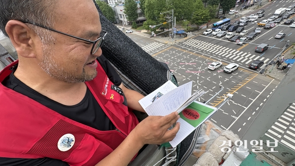 6일 오후 택시기사 최저임금 보장을 위한 근로기준법 시행령 개정을 촉구하며 인천 남동구 통신탑에 올라 고공농성에 나선 택시기사 고영기씨가 동료 노조원과 시민사회단체 활동가들이 보낸 편지를 읽고 있다. 2026.7.6 /정선아기자 sun@kyeongin.com