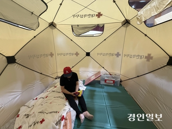 쿠팡물류센터 화재로 신현초 대피소에 온 석남동 주민이 텐트 안에서 휴식을 취하고 있다. 2026.7.19 /조경욱기자 imjay@kyeongin.com