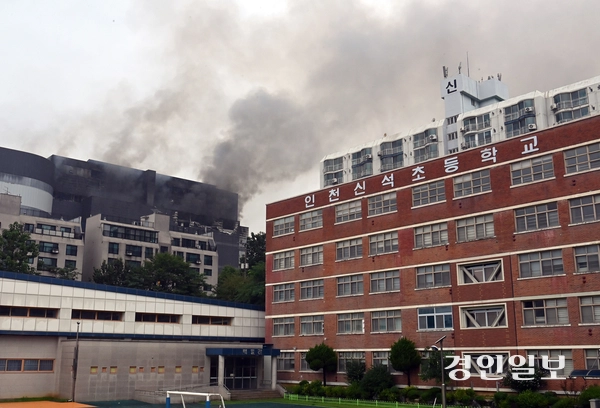 20일 인천시 서해구 쿠팡화재의 영향으로 임시 휴교한 인천 서해구 신석초등학교 옆으로 화염과 연기가 치솟고 있는 쿠팡 물류센터가 보인다. 2026.7.20 /김용국기자 yong@kyeongin.com