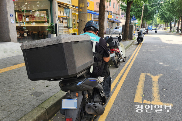 지난 28일 낮 기온이 30도가 넘는 찜통 더위를 피해 인천시 남동구 구월동의 그늘진 도로에서 이동노동자가 오토바이에 앉아 있다. 2026.7.29 /김용국기자 yong@kyeongin.com