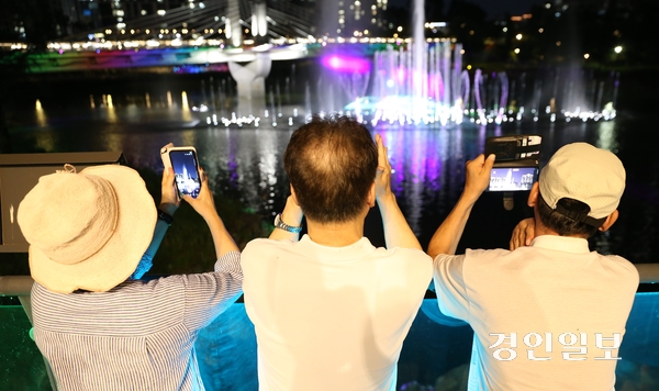 지난 7일 오후 8시 위례호수공원을 산책하던 시민들이 워터스크린이 시범적으로 운영되자 휴대폰으로 영상을 찍고 있다. 위례호수공원 워터스크린은 오는 13일부터 정식 운영될 예정이다. 2026.8.7 하남/문성호기자 moon23@kyeongin.com