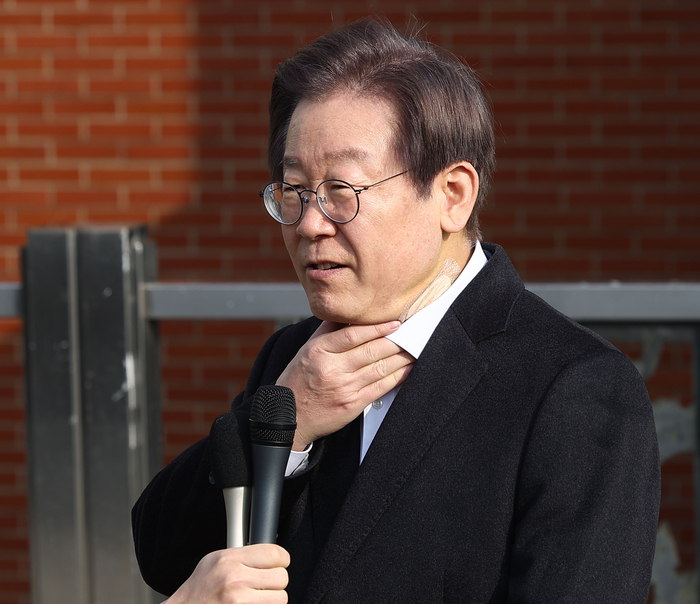 목 만지며 발언하는 이재명 대표