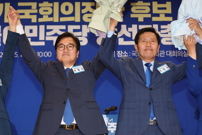 더불어민주당 국회의장 후보로 선출된 우원식 후보(왼쪽)와 국회부의장 후보로 선출된 이학영 후보가 16일 오전 국회 의원회관에서 열린 제22대 전반기 국회의장단 후보 선출을 위한 당선자 총회에서 꽃다발을 들고 두 팔을 들어 올리고 있다. 2024.5.16 / 연합뉴스